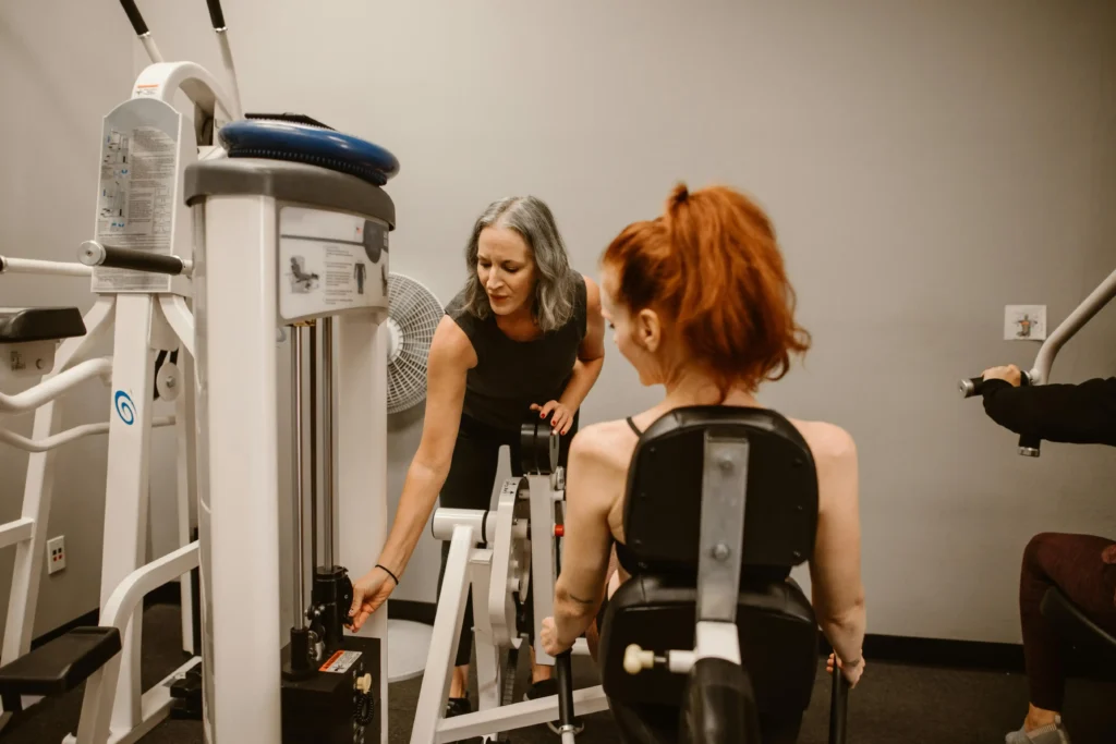 Female fitness trainer guiding a woman on strength training machine at Herburn Studio ladies-only fitness centre