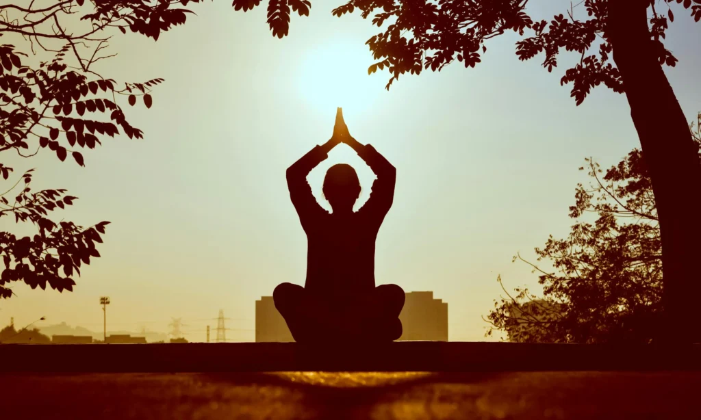Person practicing morning yoga and meditation outdoors at Herburn Studio ladies-only fitness centre in Anchalummood, Kollam